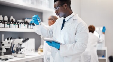 Science, research and black man test tube and tablet for medical analysis and innovation in laboratory. Pharmaceutical analytics, medicine study and scientist in South Africa checking vaccine results