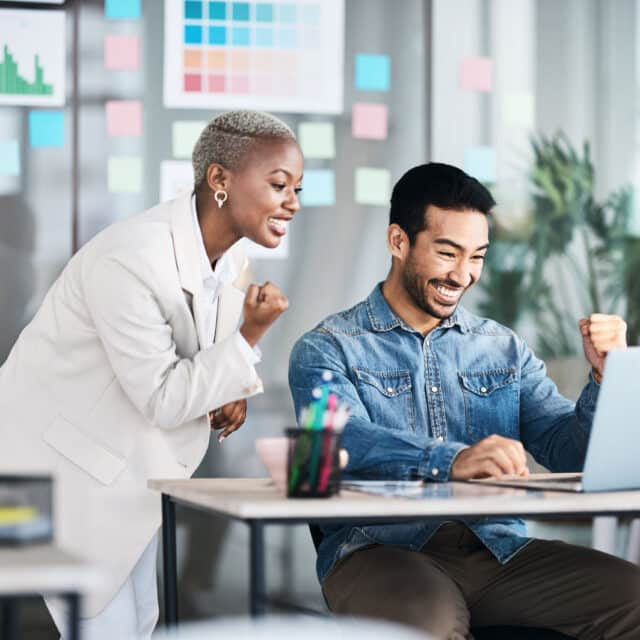 A man and woman are consulting on a laptop in a global office.