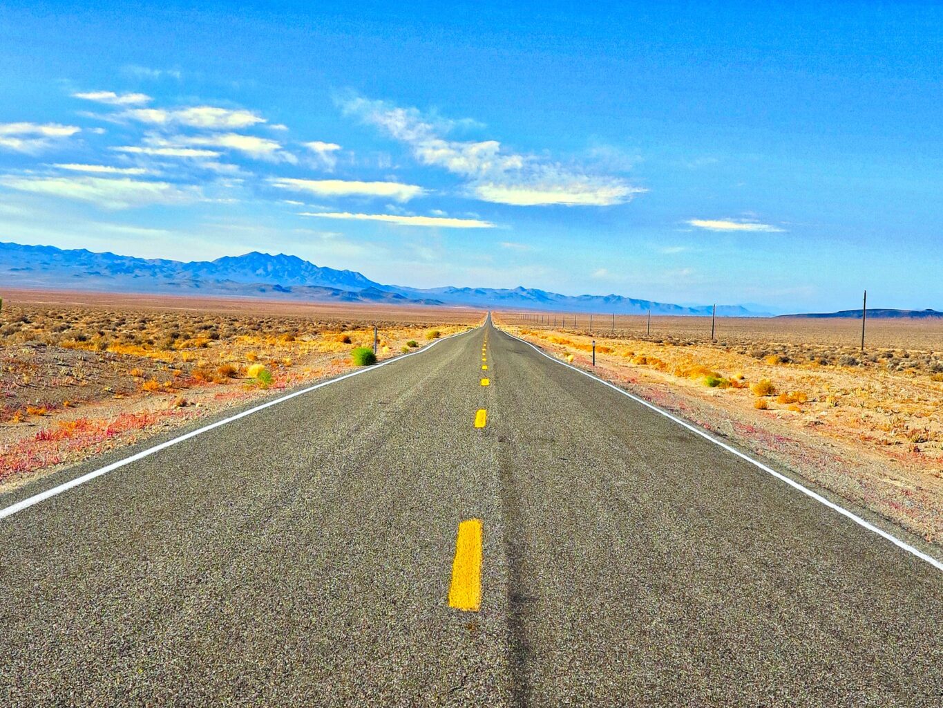 A strategic road in a global desert landscape with majestic mountains in the background.