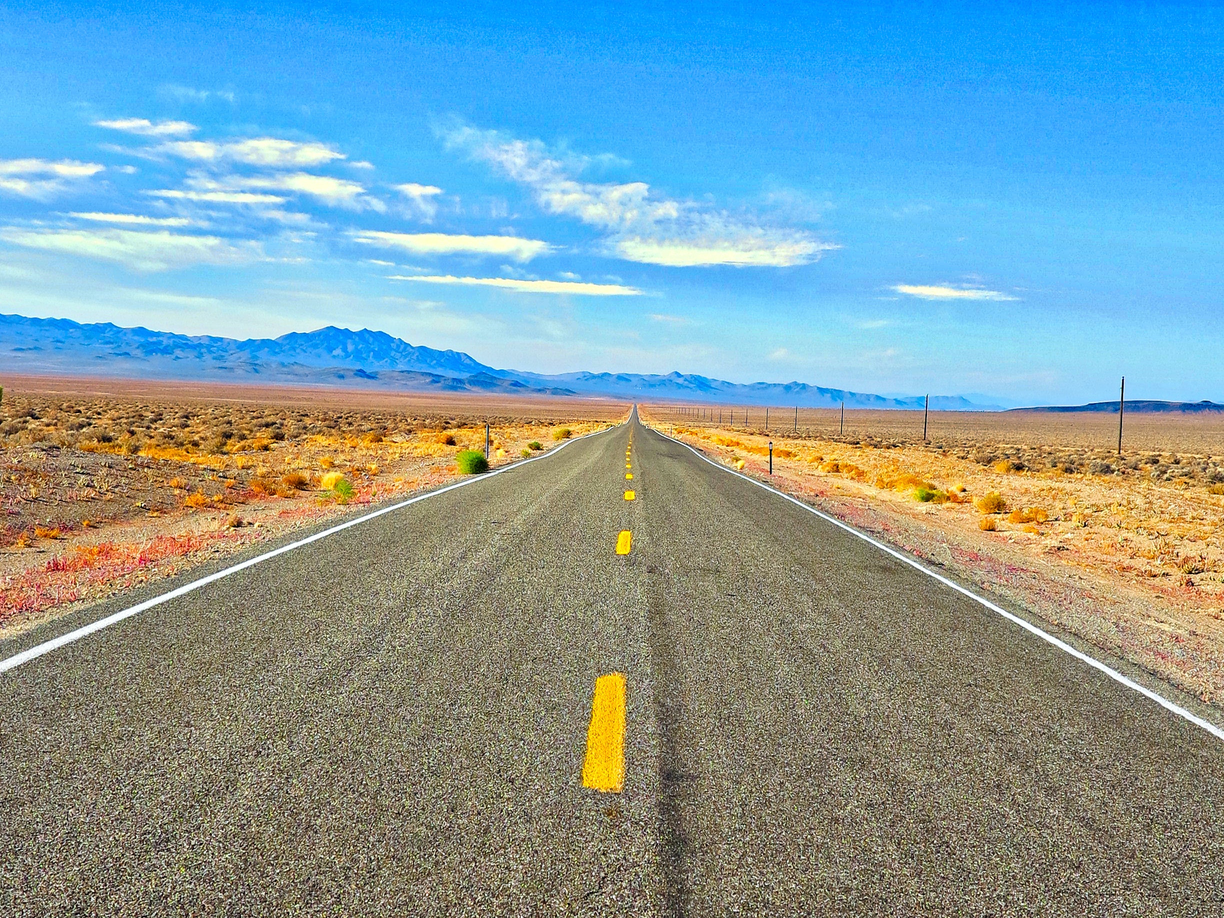 A strategic road in a global desert landscape with majestic mountains in the background.