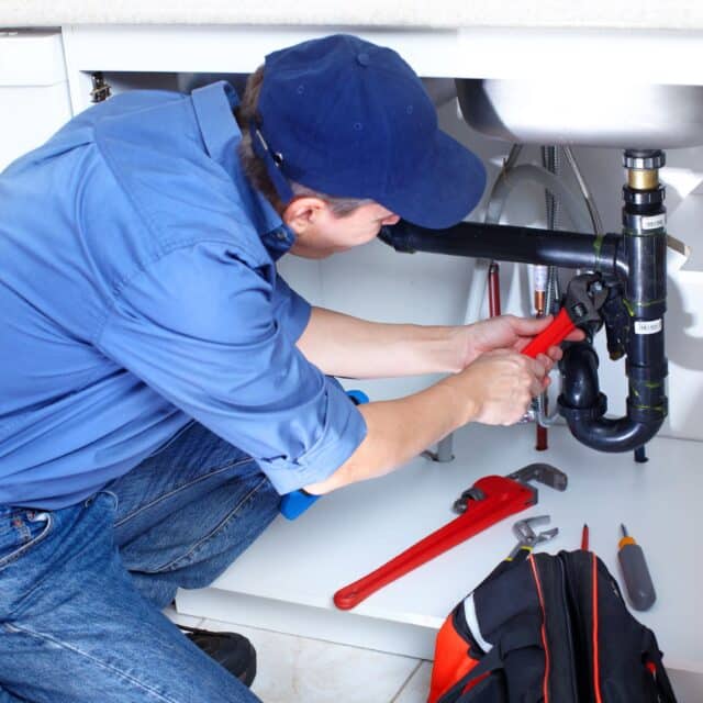 A tech company innovating plumbing services by having a plumber working on a sink.