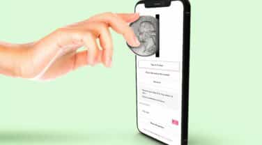 A hand holding a coin on a smartphone screen, showcasing the strategic integration of tech in the company.
