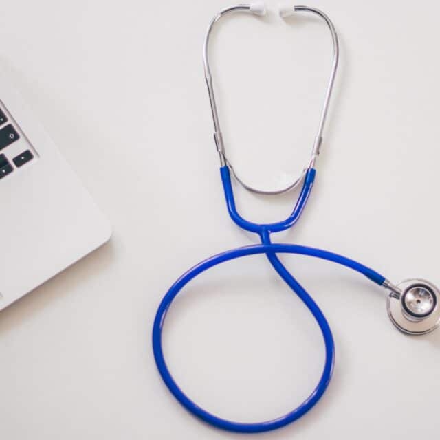 A strategic company embraces innovation with a stethoscope next to a laptop on a white table.