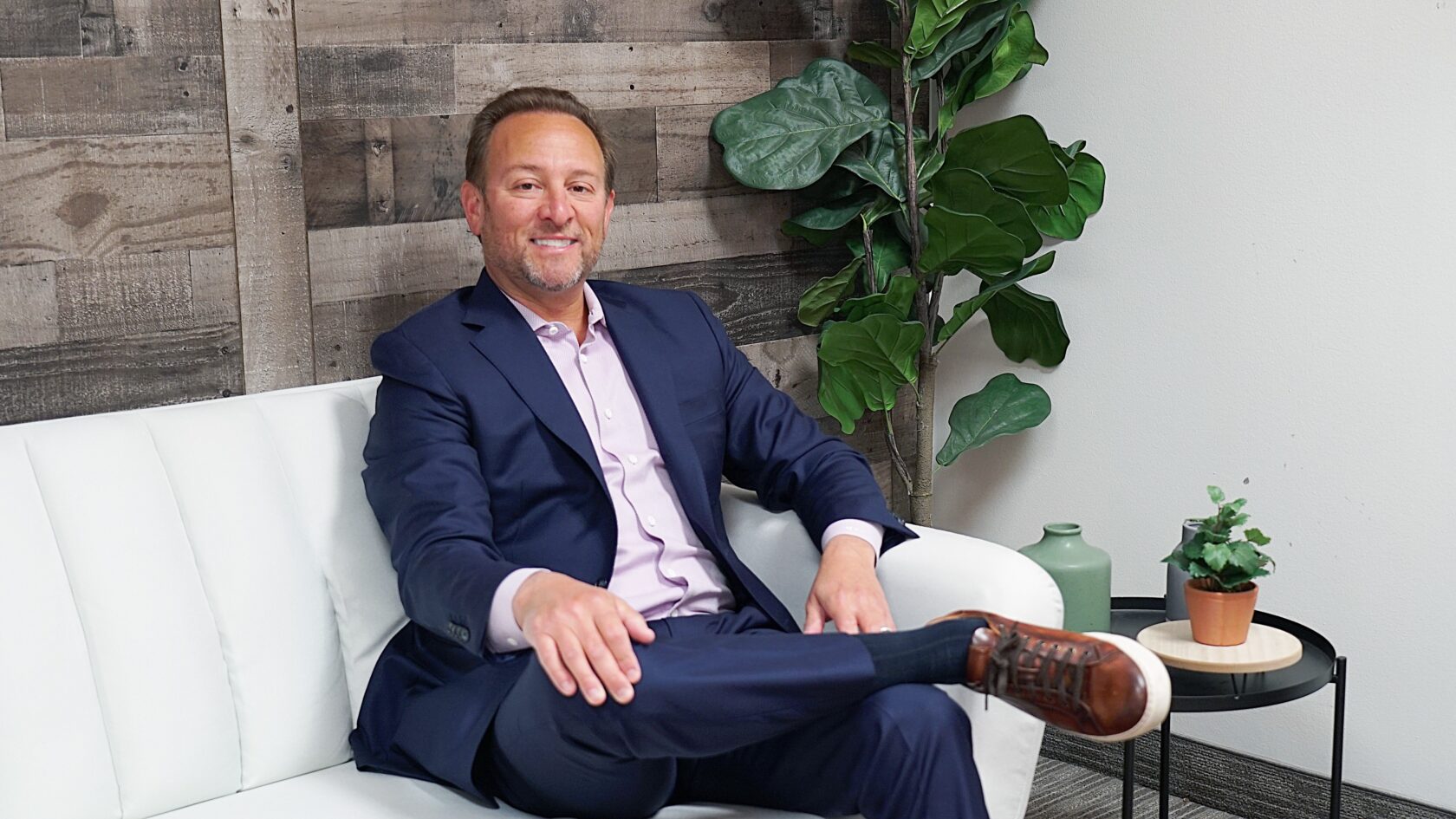 A man in a suit sitting on a white couch in a global consulting company.