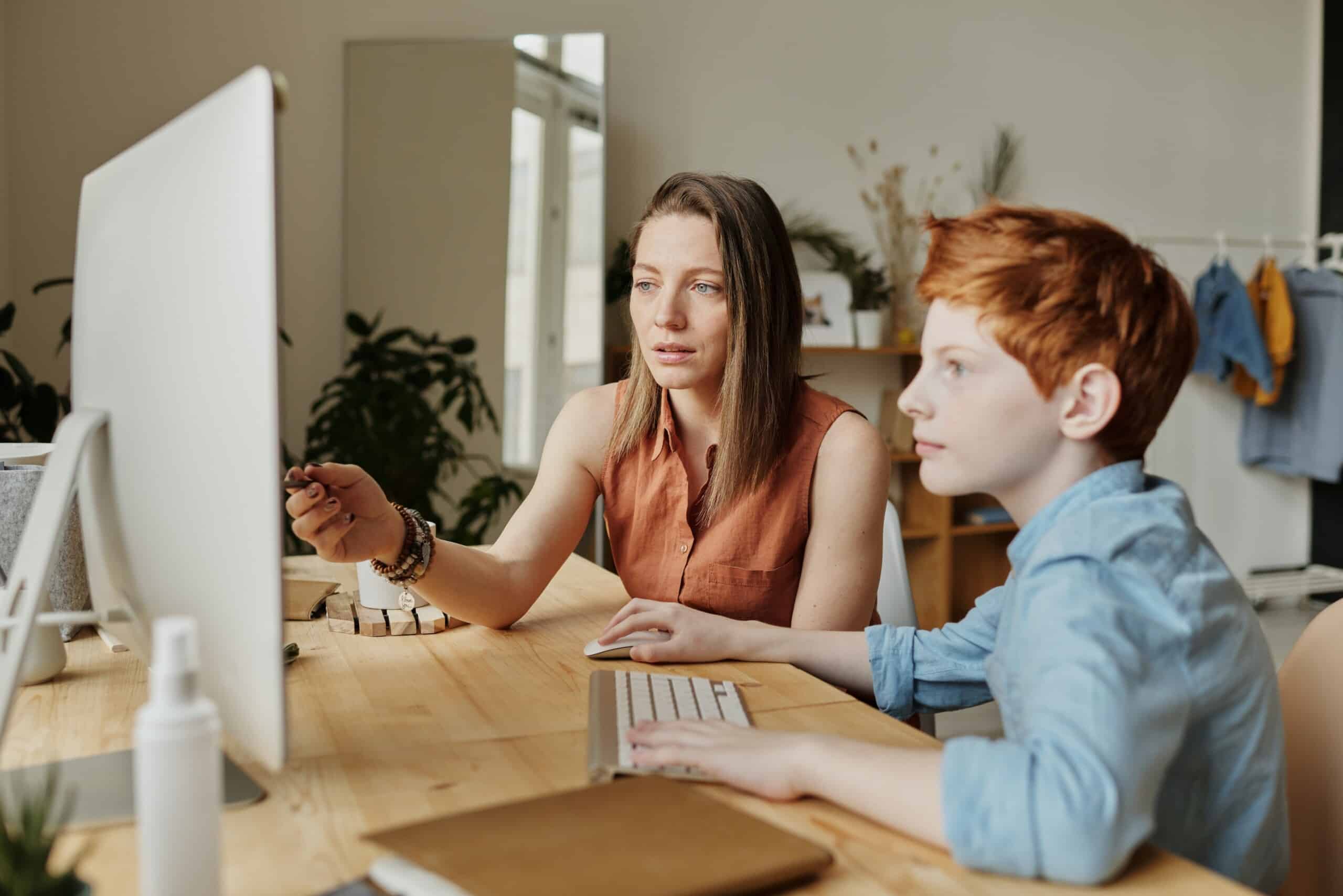 A woman and a boy working on a computer in a strategic company.