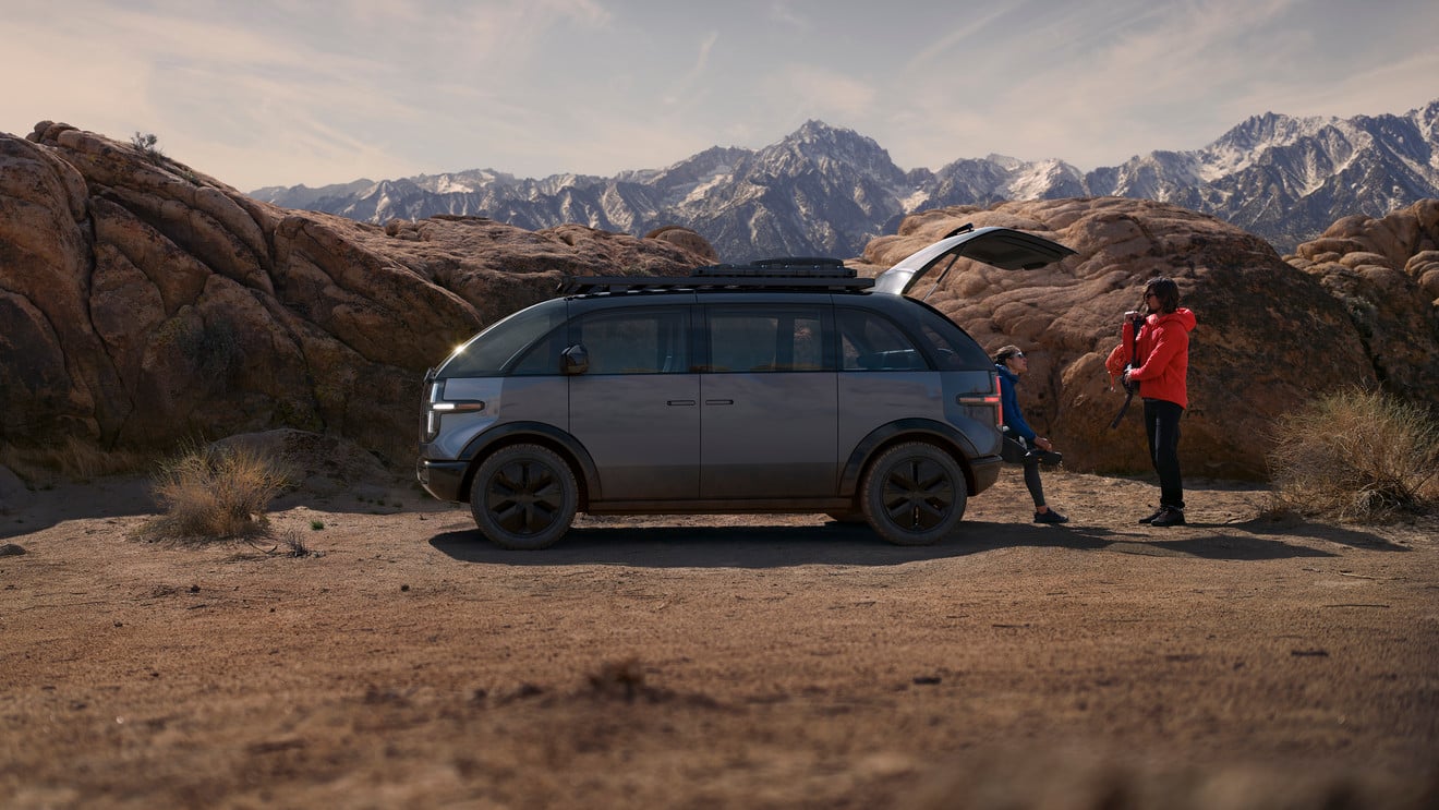 A strategic man is standing next to an innovative vehicle in the desert.