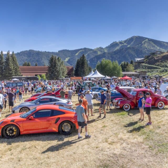 A group of innovative individuals standing in front of a lineup of tech cars.