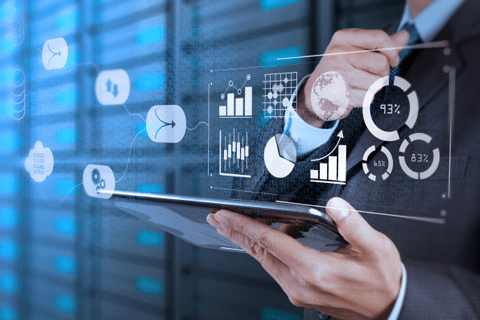 A tech-savvy man in a suit is holding a tablet in front of a server, exemplifying global innovation.