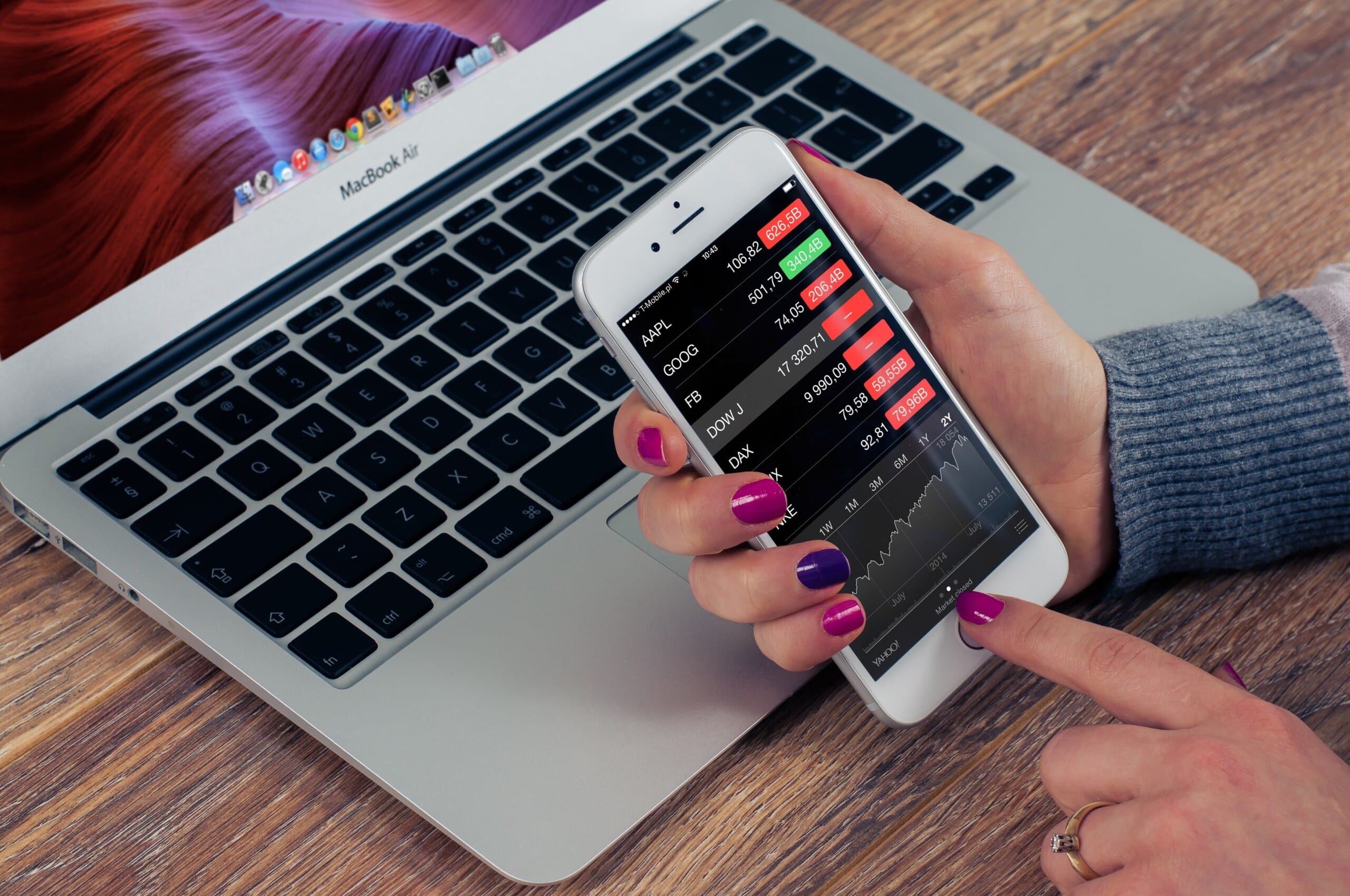 A woman holding a cell phone next to a laptop while consulting for a tech company.