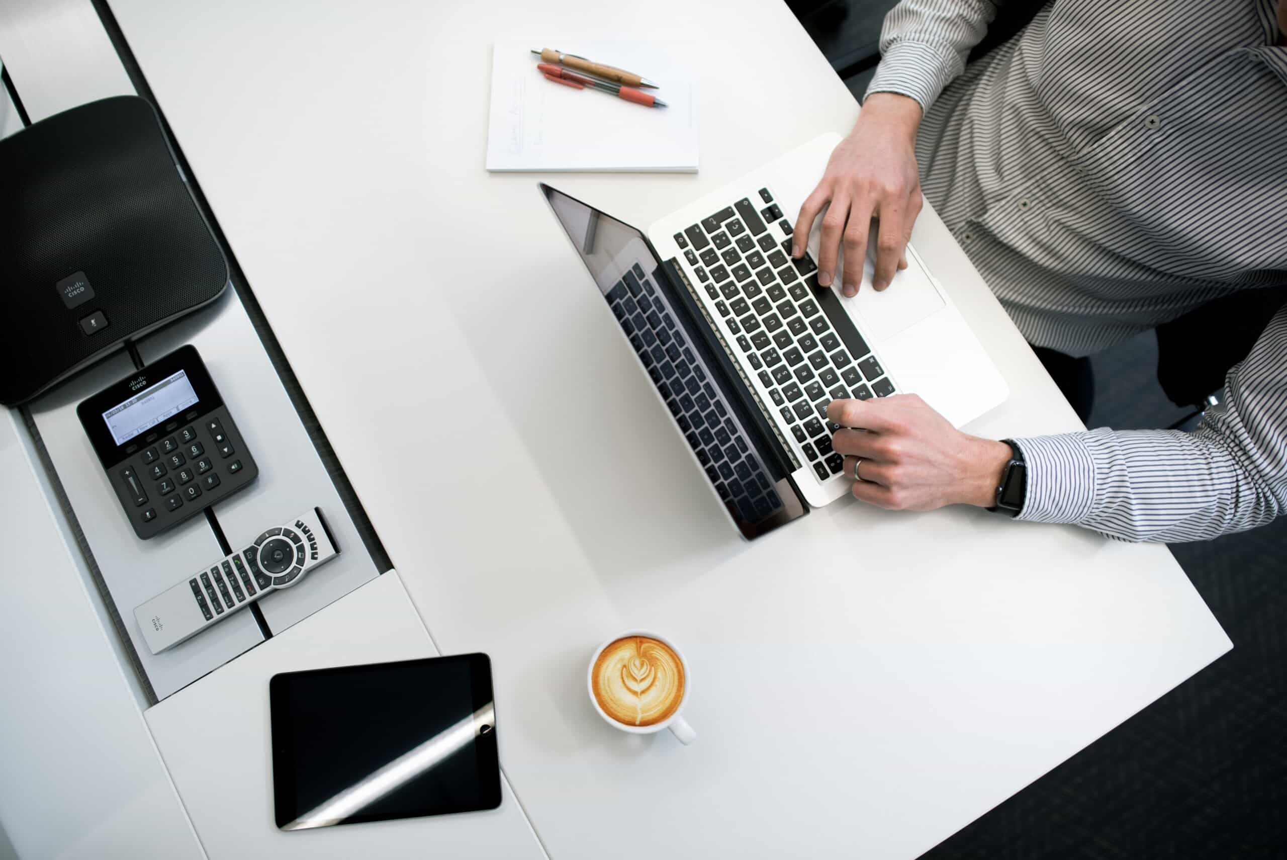 A innovative man working on a laptop at a consulting company desk.