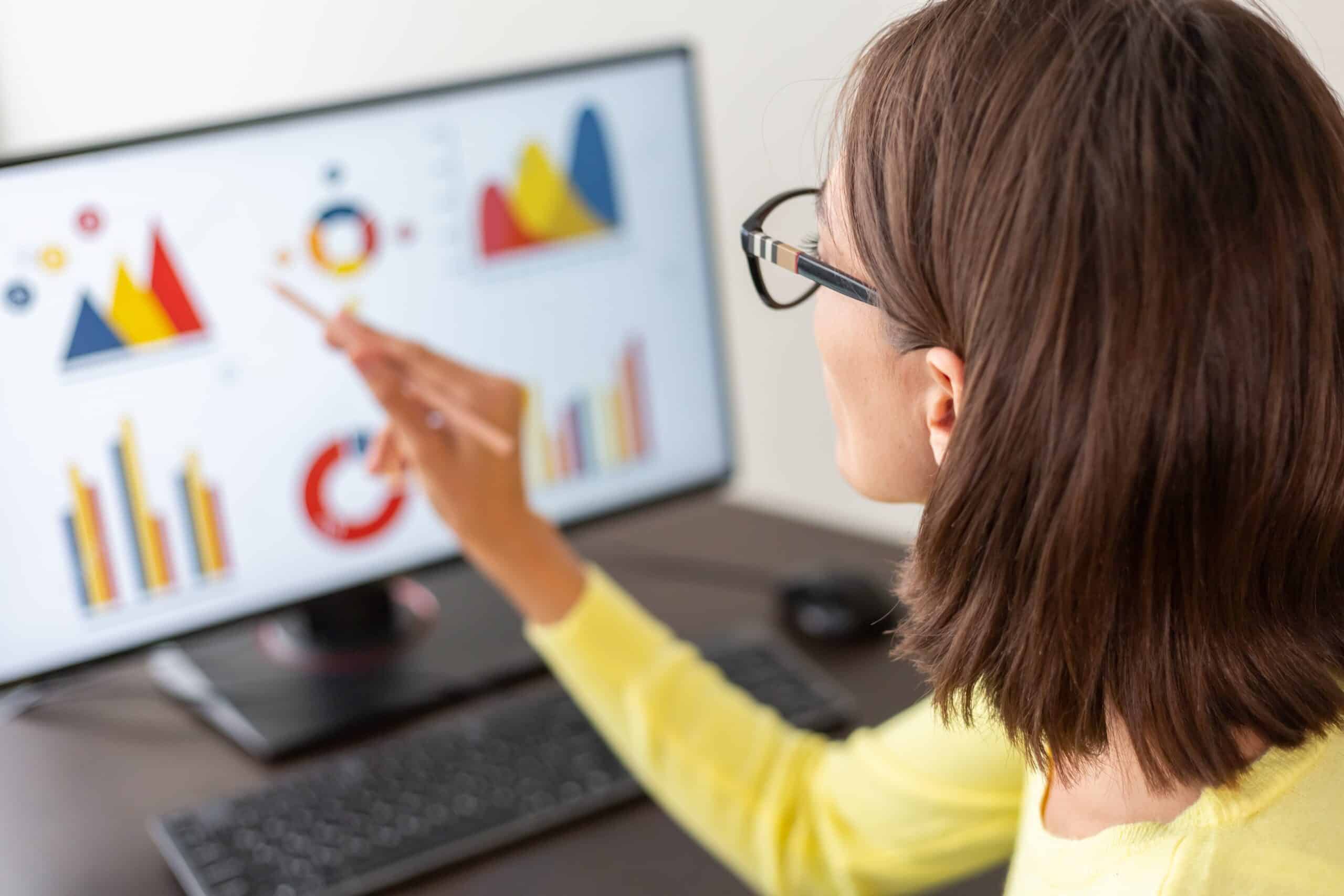 A woman is pointing at a global graph on a computer screen.