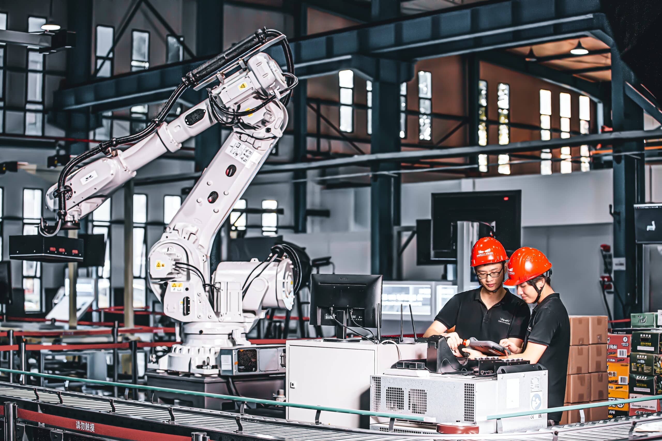 Two people collaborating with a robotic system in a factory, utilizing advanced technology.