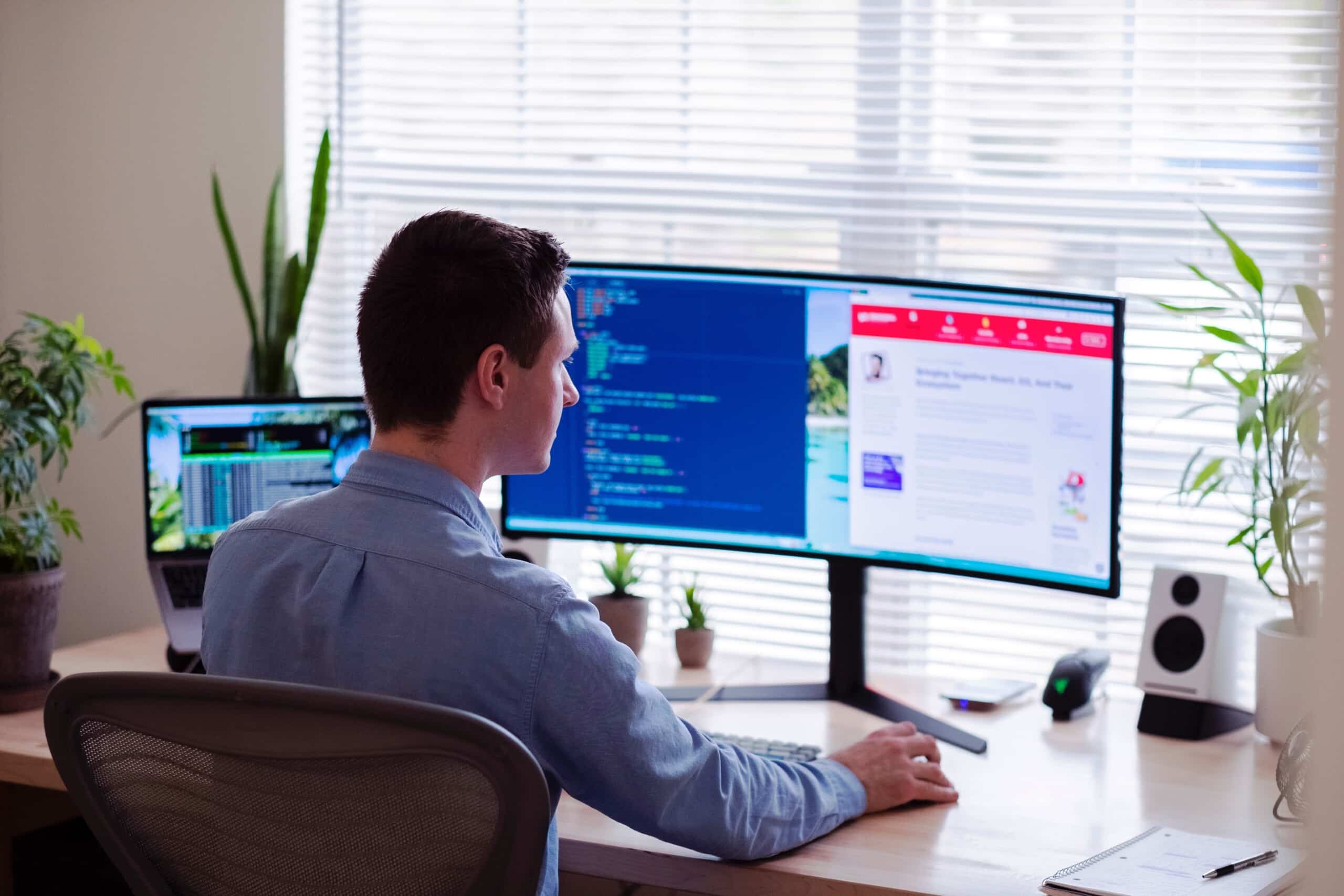 A strategic consultant sitting at a desk with two monitors, advising a company.