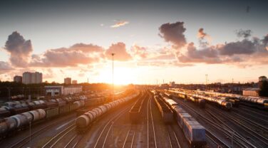 A strategically positioned train on a train track captures the beauty of a global sunset.