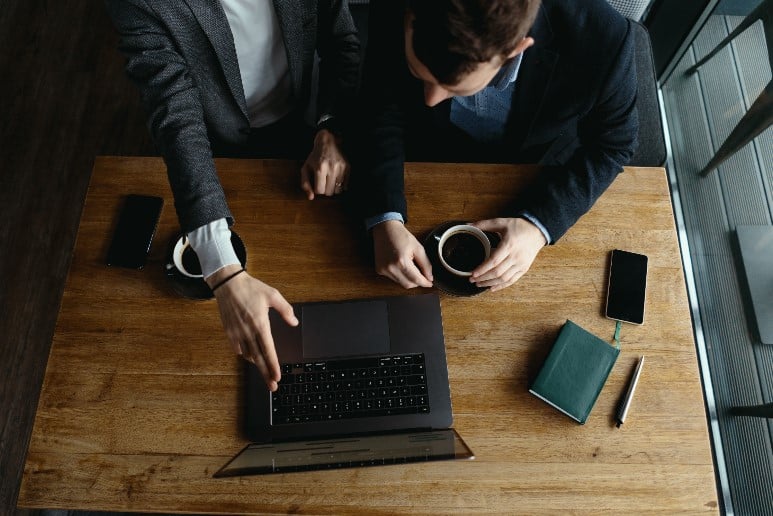 Two business people from a strategic tech company working on a laptop at a table.