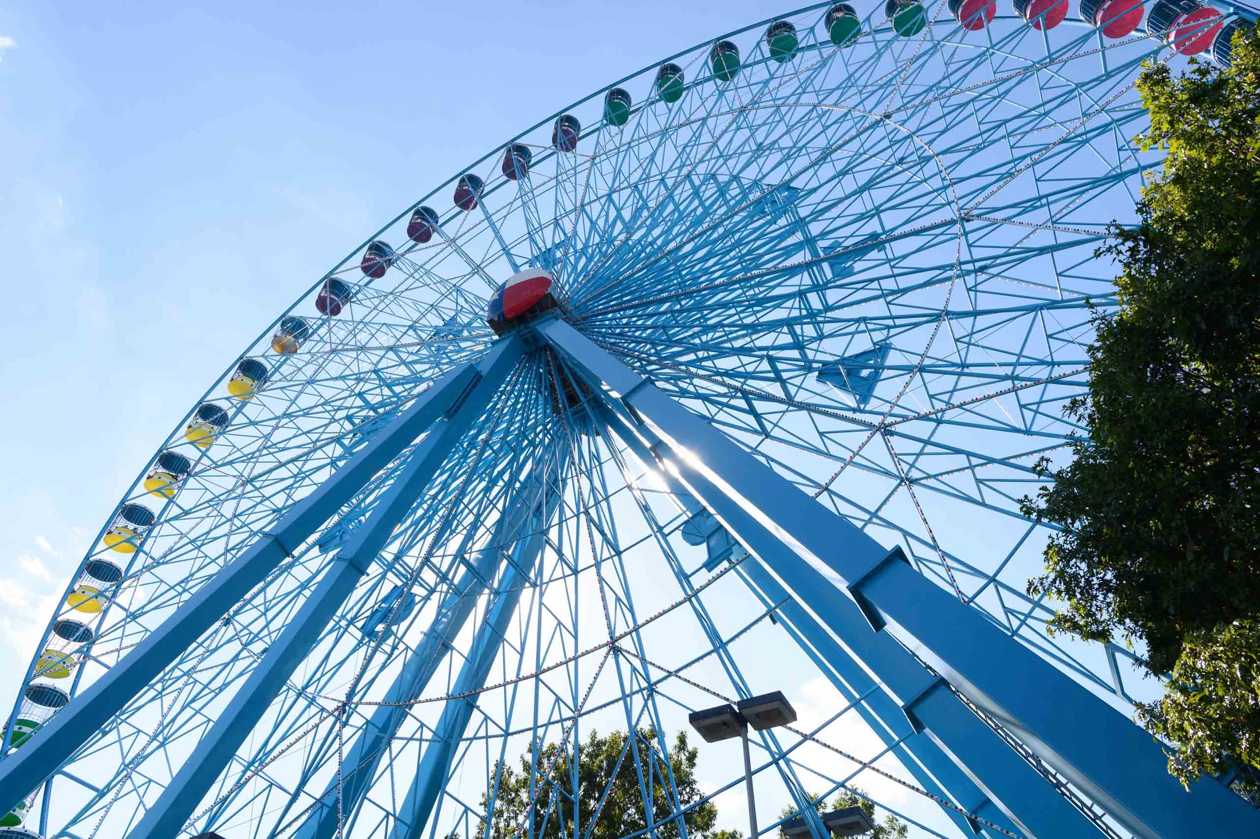 A blue ferris wheel in front of a blue sky.