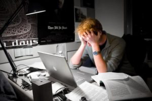 An SEO specialist sitting at a desk with a laptop in front of him, working on deliverable documentation.