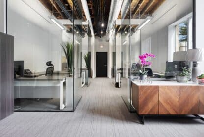 This description showcases a professional office setup with glass walls and a desk.
