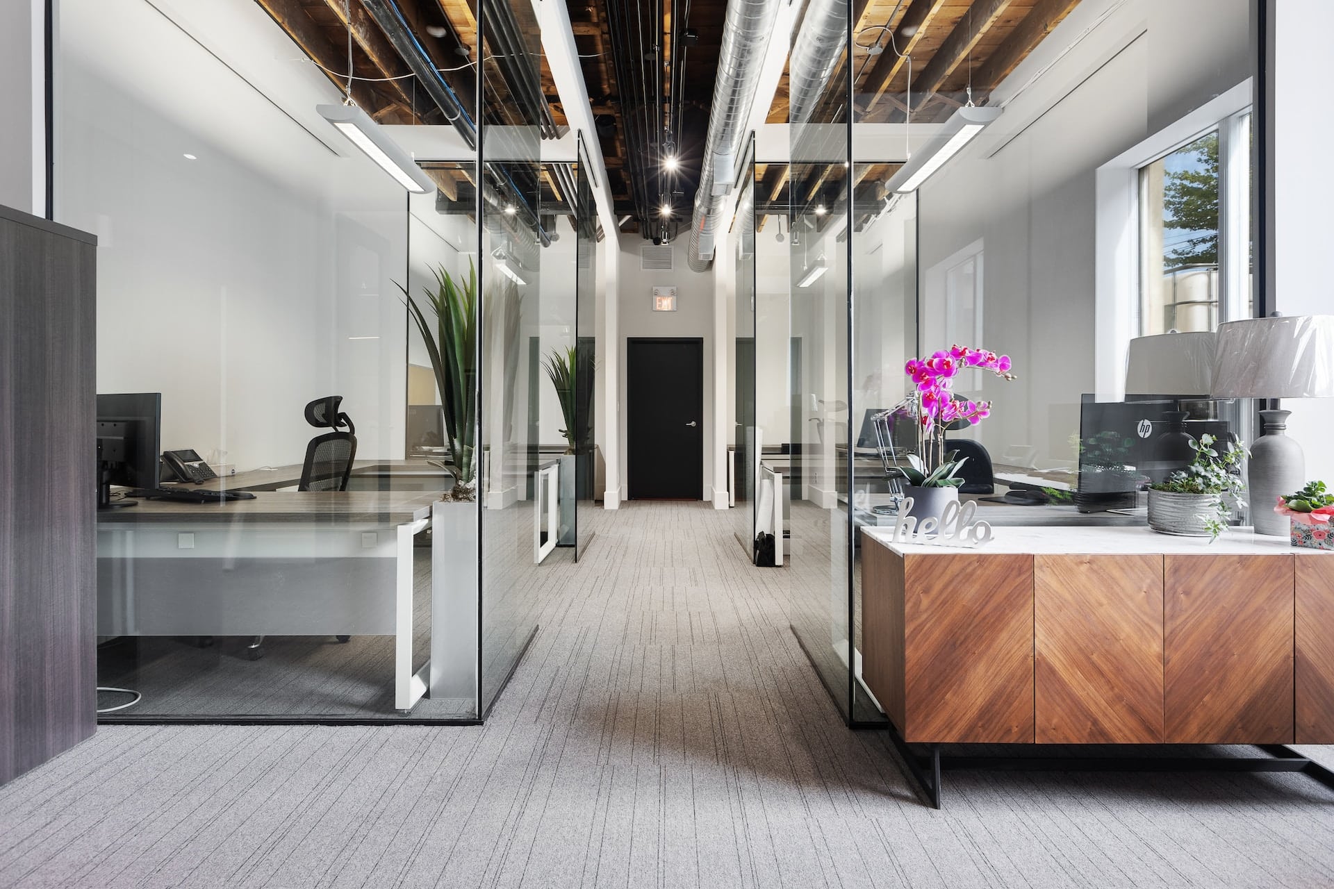 This description showcases a professional office setup with glass walls and a desk.